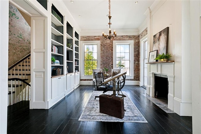 dining area featuring an inviting chandelier, dark hardwood / wood-style flooring, built in features, and brick wall