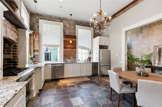 kitchen with hanging light fixtures, white cabinetry, light stone countertops, and stainless steel appliances