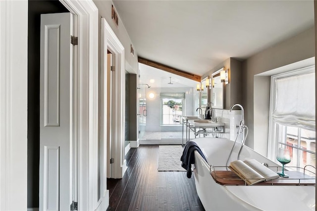 interior space featuring a bathtub, wood-type flooring, lofted ceiling with beams, and a wealth of natural light