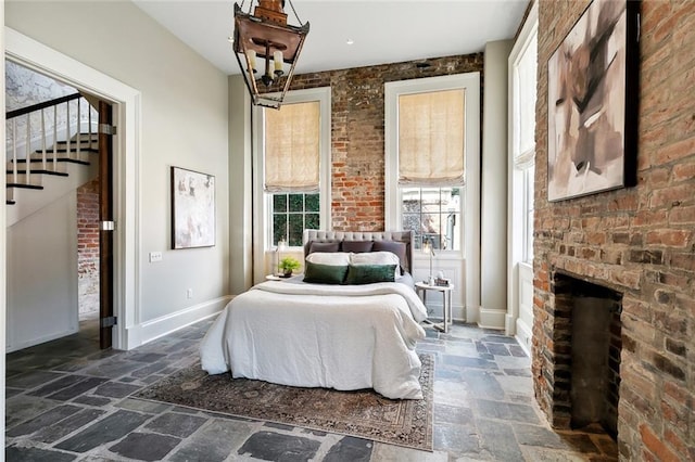 bedroom featuring a brick fireplace and brick wall