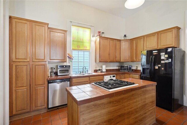 kitchen featuring sink, a kitchen island, stainless steel appliances, tile countertops, and tile patterned floors