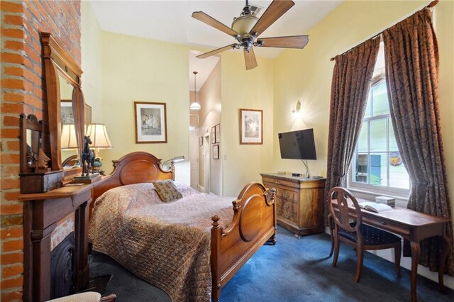 bedroom featuring lofted ceiling, dark colored carpet, multiple windows, and ceiling fan