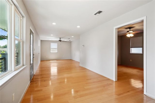 spare room featuring light wood-type flooring, ceiling fan, and plenty of natural light