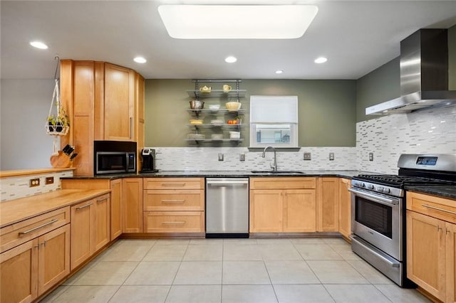 kitchen with dark stone countertops, light tile patterned flooring, wall chimney exhaust hood, stainless steel appliances, and sink