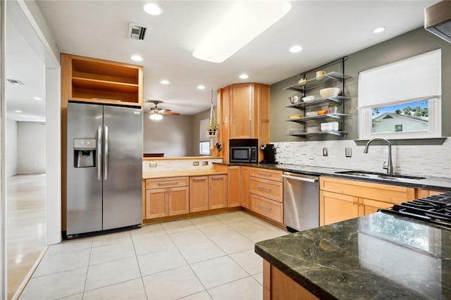 kitchen featuring dark stone countertops, backsplash, stainless steel appliances, ceiling fan, and sink