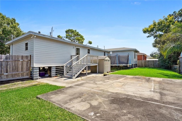 rear view of property with a lawn, a patio, and a trampoline