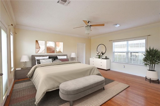 bedroom with a textured ceiling, crown molding, hardwood / wood-style floors, and ceiling fan