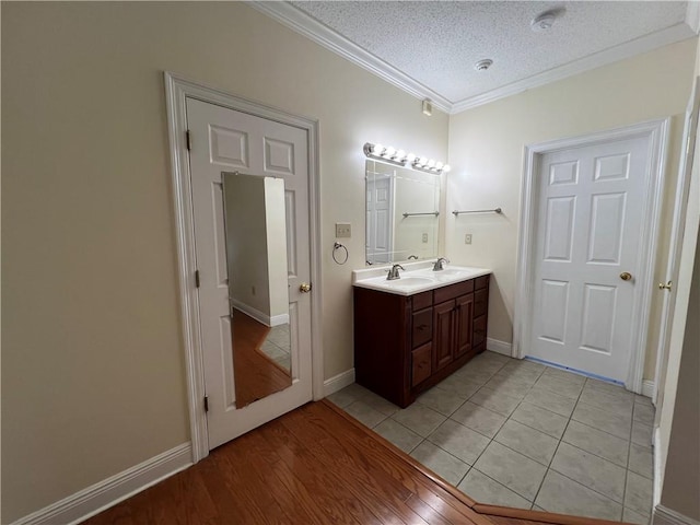 bathroom featuring a textured ceiling, ornamental molding, vanity, and hardwood / wood-style floors