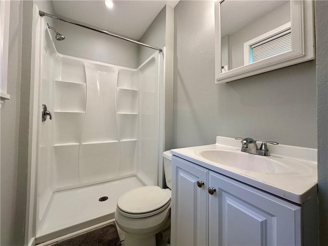 bathroom with vanity, toilet, and a shower