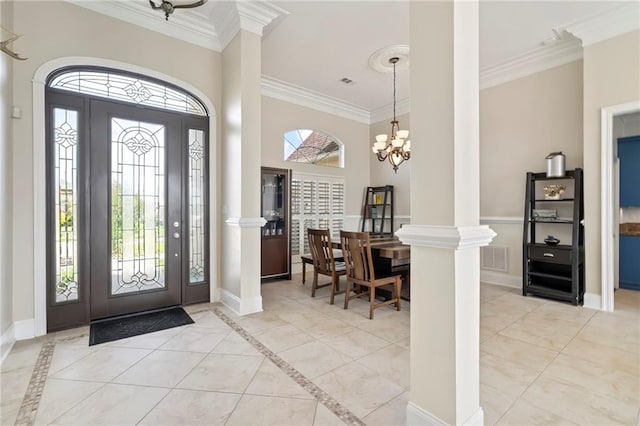 tiled entryway featuring crown molding, a notable chandelier, and ornate columns