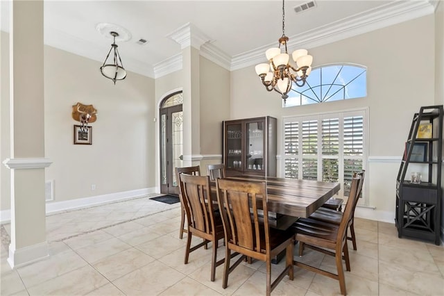 dining room with a towering ceiling, ornamental molding, decorative columns, and an inviting chandelier