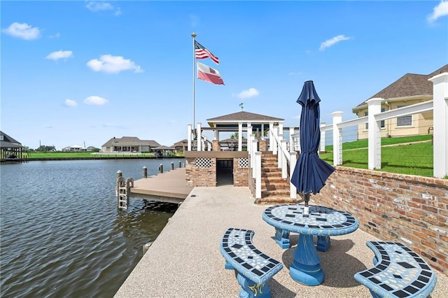 view of dock with a gazebo, a yard, and a water view