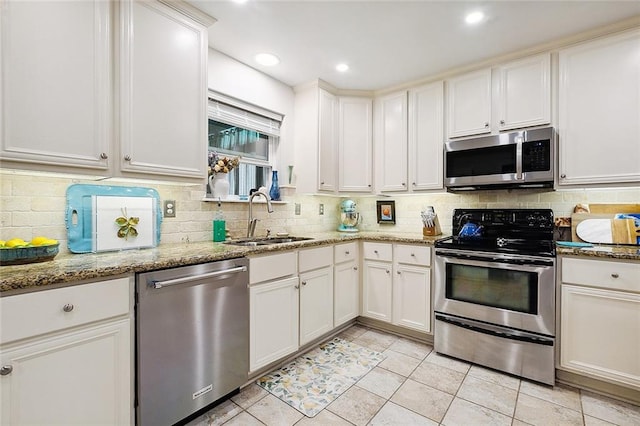 kitchen with appliances with stainless steel finishes, light stone countertops, sink, and white cabinets