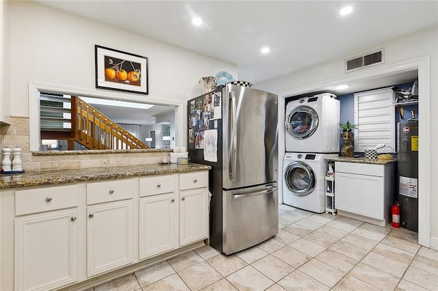 washroom featuring light tile patterned flooring, stacked washer / dryer, and water heater