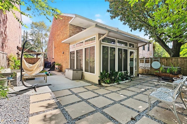 rear view of property with a sunroom and a patio area