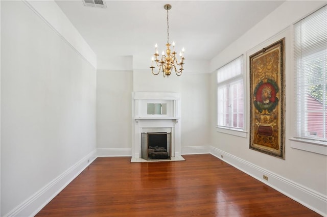 unfurnished living room featuring a notable chandelier, dark hardwood / wood-style floors, and a wealth of natural light