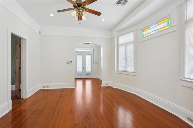 empty room with french doors, ceiling fan, and dark wood-type flooring