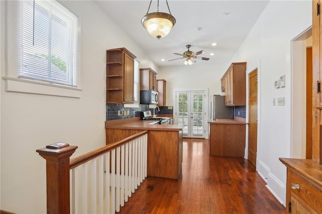 kitchen featuring ceiling fan, hanging light fixtures, stainless steel appliances, dark hardwood / wood-style flooring, and decorative backsplash