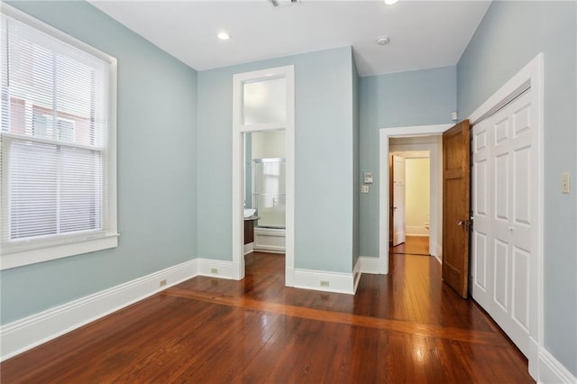 unfurnished bedroom with dark hardwood / wood-style floors, ensuite bath, and a closet