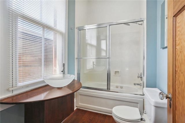 full bathroom featuring hardwood / wood-style floors, combined bath / shower with glass door, vanity, and toilet