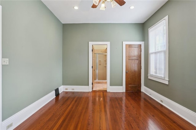 unfurnished bedroom with ceiling fan, ensuite bathroom, and dark wood-type flooring