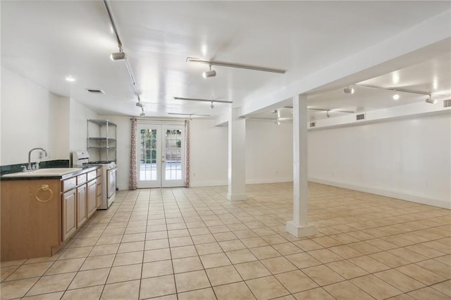 kitchen with light tile patterned floors, sink, french doors, rail lighting, and white range with gas stovetop