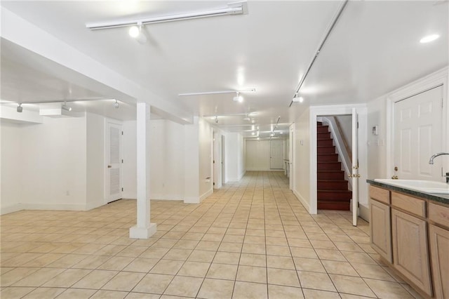 basement featuring light tile patterned floors and sink