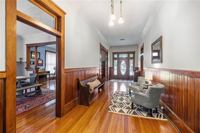 foyer entrance with wood-type flooring, ornamental molding, and a healthy amount of sunlight