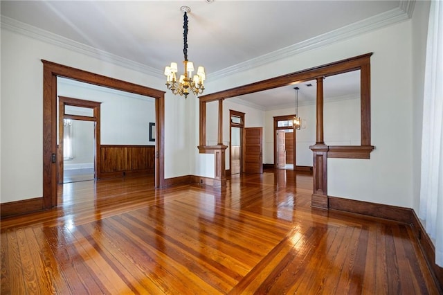 empty room with wood-type flooring, ornamental molding, and a notable chandelier