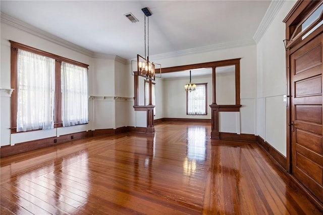 spare room featuring crown molding, dark hardwood / wood-style flooring, and an inviting chandelier