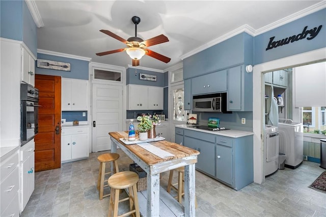 kitchen with black appliances, washer and dryer, white cabinets, and blue cabinetry