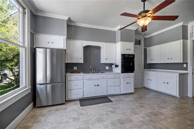 kitchen featuring stainless steel refrigerator, black oven, white cabinets, and a wealth of natural light