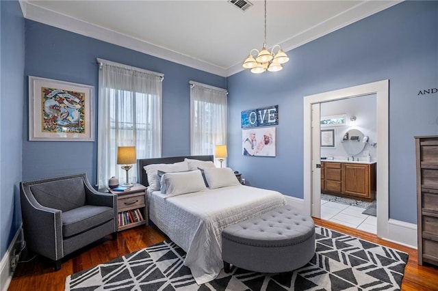 bedroom featuring ensuite bathroom, crown molding, dark wood-type flooring, sink, and an inviting chandelier