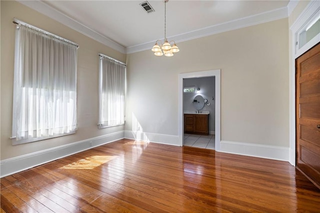 unfurnished room with a notable chandelier, light wood-type flooring, and ornamental molding