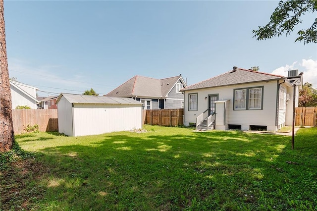 rear view of house featuring a yard and a storage unit