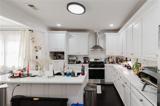 4670 Marigny St, New Orleans, LA 70122 - kitchen with stainless steel gas range, wall chimney exhaust hood, white cabinets, a breakfast bar, and light countertops