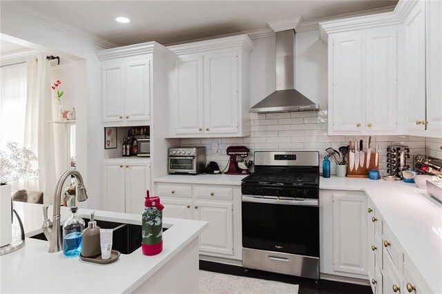 4670 Marigny St, New Orleans, LA 70122 - kitchen with gas range, wall chimney exhaust hood, white cabinetry, tasteful backsplash, and light countertops