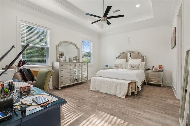 bedroom with ornamental molding, light wood-type flooring, a tray ceiling, and ceiling fan