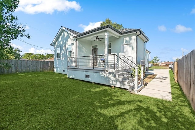 rear view of property featuring ceiling fan and a yard