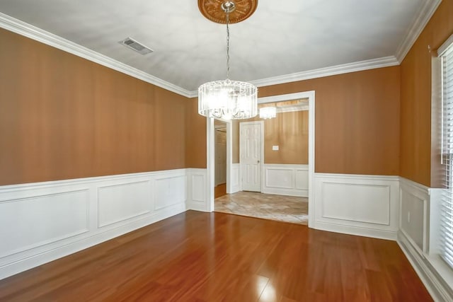 unfurnished room with ornamental molding, an inviting chandelier, and hardwood / wood-style floors