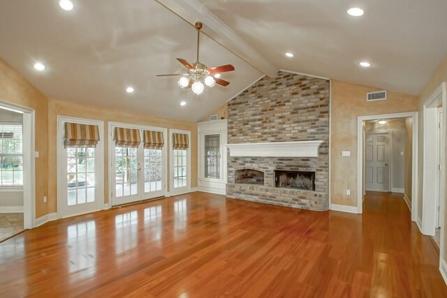 unfurnished living room with ceiling fan, beam ceiling, wood-type flooring, high vaulted ceiling, and a fireplace