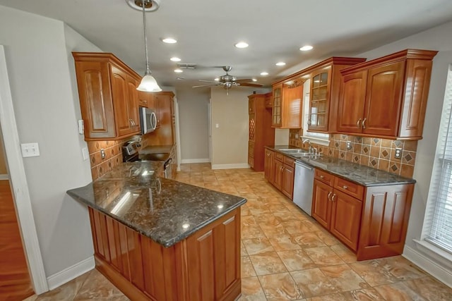 kitchen featuring pendant lighting, backsplash, kitchen peninsula, and appliances with stainless steel finishes