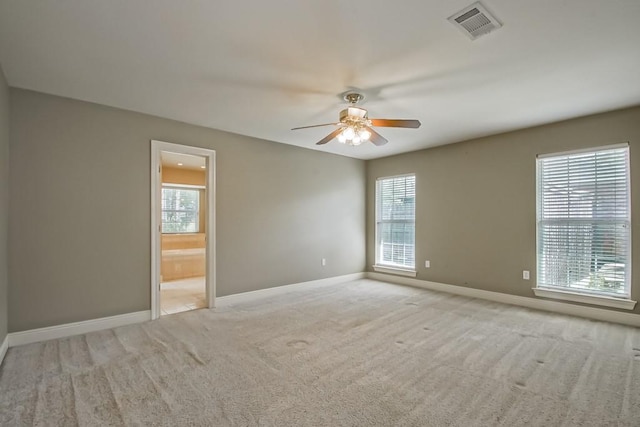 spare room featuring a healthy amount of sunlight, ceiling fan, and light carpet