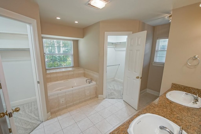 bathroom featuring vanity, a relaxing tiled tub, and tile patterned flooring