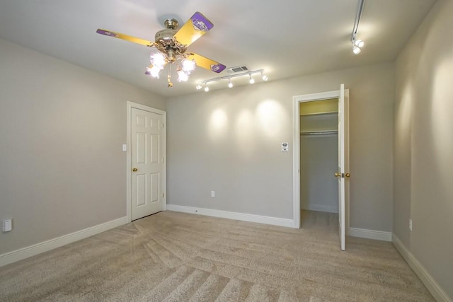 spare room with light carpet, track lighting, and ceiling fan