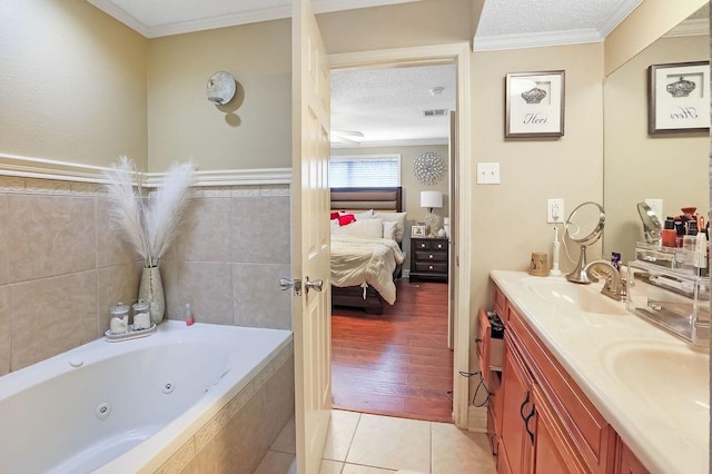 bathroom featuring vanity, a textured ceiling, crown molding, tile patterned flooring, and a relaxing tiled tub