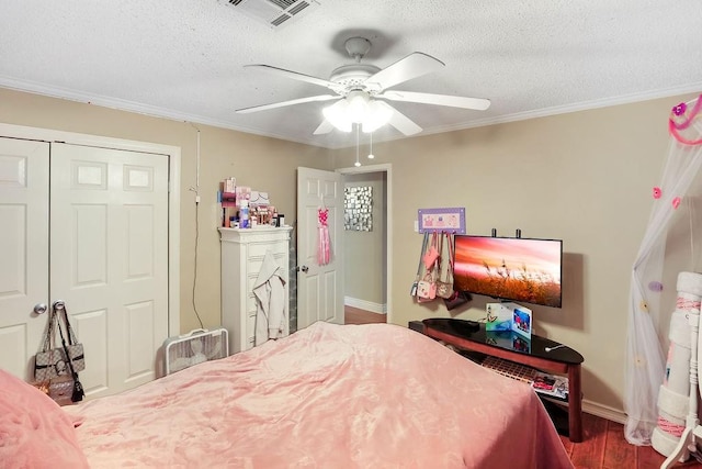 bedroom featuring a closet, a textured ceiling, hardwood / wood-style flooring, ornamental molding, and ceiling fan