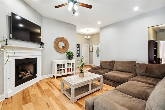 living room featuring light wood-type flooring and ceiling fan with notable chandelier