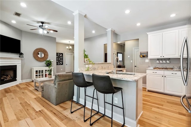 kitchen featuring white cabinets, a breakfast bar area, light wood-type flooring, and light stone countertops