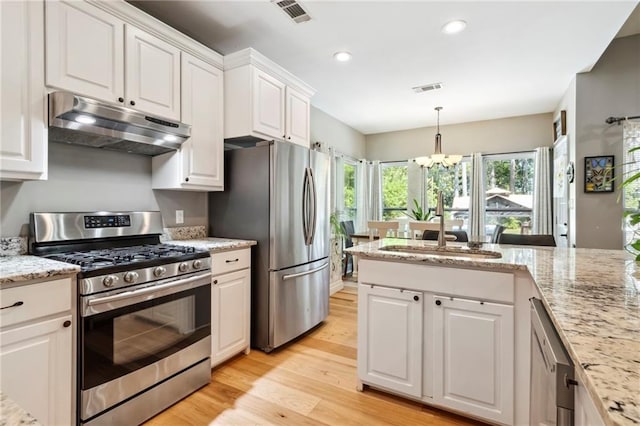 kitchen with light wood-type flooring, light stone counters, a notable chandelier, white cabinetry, and appliances with stainless steel finishes